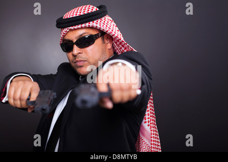 middle eastern bodyguard posing with guns on black background Stock Photo