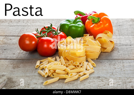 Pasta and Vegetables on Rustic Background - raw bronze die pasta and vegetables on a rustic wooden background, over white... Stock Photo