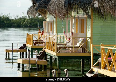 Thatch roofed bungalows on stilts in lagoon at Colon Island, Punta Caracol Hotel Stock Photo