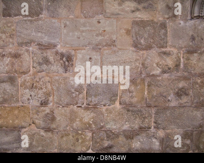 Close-up of a large stone wall, displaying its rough, textured surface. The wall is constructed from various stones, showing a natural pattern and solid structure. It represents traditional masonry work and may be part of an old building or fortification. Stock Photo