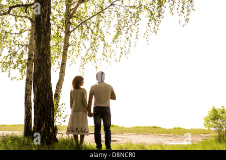 Happy young couple holding hands under birch tree isolated on white background Stock Photo