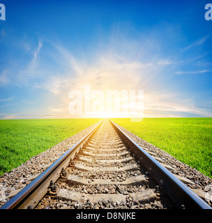 Railway to the sun through green field Stock Photo