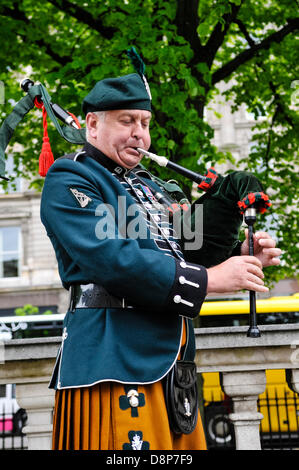 2nd June 2013, Belfast, Northern Ireland.  A piper plays a lament on bagpipes at Belfast City Hall, to commemorate the men and women who served under the UDR during The Troubles. Stock Photo