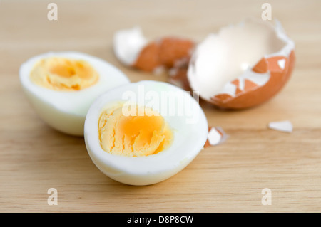 Hard boiled egg cut in half with egg shell on wooden chopping board Stock Photo