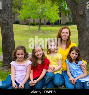Mother teacher with daughter pupils in playground park group portrait on lawn Stock Photo