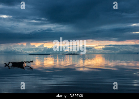 Small outrigger bangka - a traditional Filipino fishing boat - in calm evening waters Stock Photo