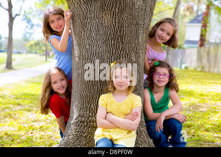 Children group of sisters girls and friends playing on tree trunk at the park outdoor Stock Photo