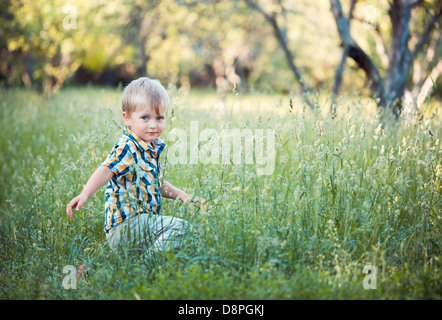A cute little baby boy sit in the grass in park Stock Photo