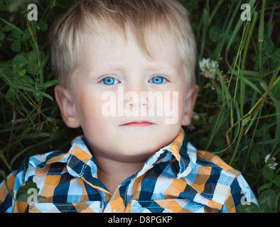 A cute little boy lying in a field of green in the park Stock Photo