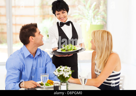 happy waitress serving customers in restaurant