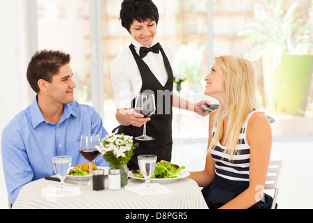 waitress serving wine to diners in modern restaurant Stock Photo