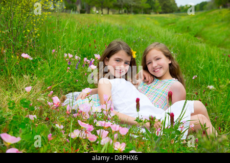 children friends girls on spring meadow with poppy flowers Stock Photo