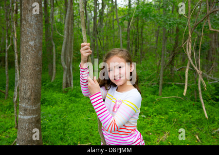 Happy children girl playing in forest park jungle with liana smiling Stock Photo