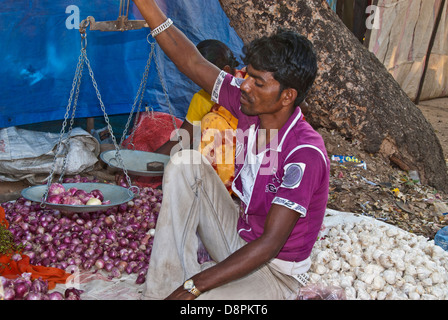 East Indian vendor weighing onions at Indian marketplace in Mocha Village, Madhya Pradesh, India Stock Photo