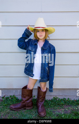 Little kid girl pretending to be a cowboy with father boots and hat Stock Photo