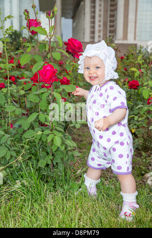 Smiling pretty little child girl with flower rose in park Stock Photo