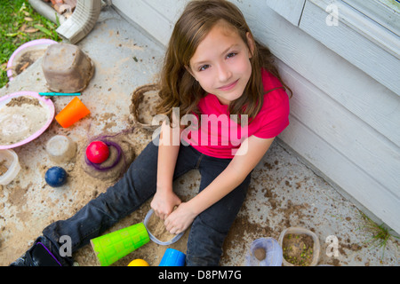 girl playing with mud in a messy soil smiling portrait looing from high point Stock Photo