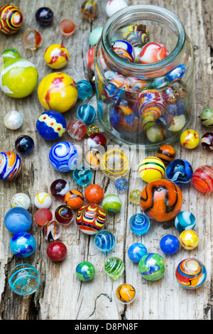 Colourful marbles and glass jar on old wood Stock Photo