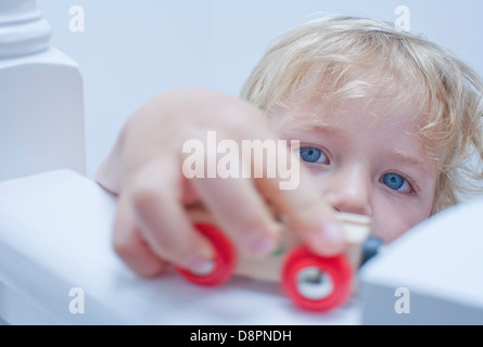 Little boy playing toy car on banister Stock Photo