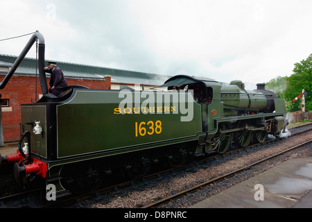 Man filling up water tank of a steam train engine Stock Photo