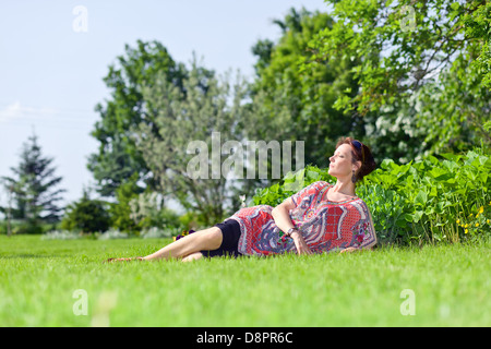 The woman of middle age has a rest on a grass in park Stock Photo