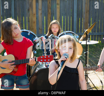 Blond kid singer girl singing playing live band in backyard concert with friends Stock Photo