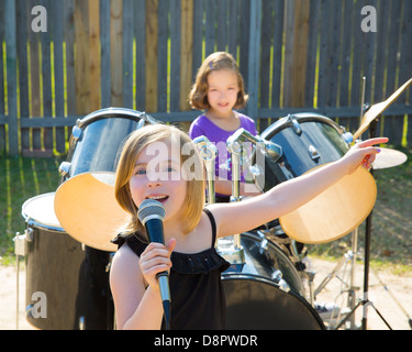Blond kid singer girl singing playing live band in backyard concert with friends Stock Photo