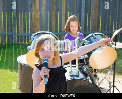 Blond kid singer girl singing playing live band in backyard concert with friends Stock Photo