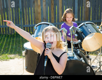 Blond kid singer girl singing playing live band in backyard concert with friends Stock Photo