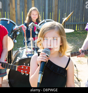 Blond kid singer girl singing playing live band in backyard concert with friends Stock Photo