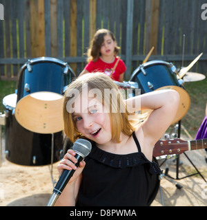 Blond kid singer girl singing playing live band in backyard concert with friends Stock Photo