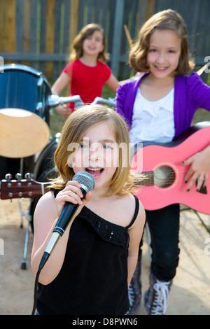 Blond kid singer girl singing playing live band in backyard concert with friends Stock Photo