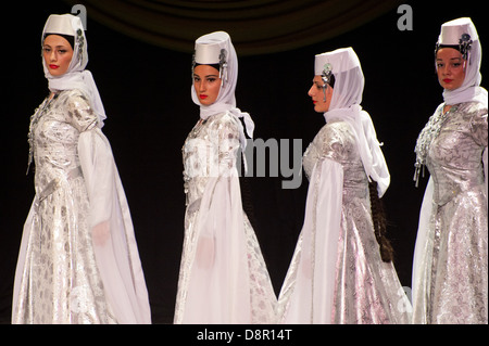 Georgian children dressed with traditional costumes dancing a folklore dance show on stage. Stock Photo