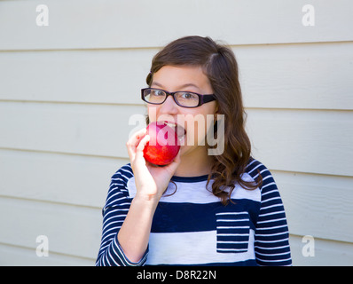 Teenager girl happy eating a red apple Stock Photo