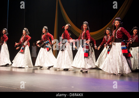 Georgian children dressed with traditional costumes dancing a folklore dance show on stage. Stock Photo