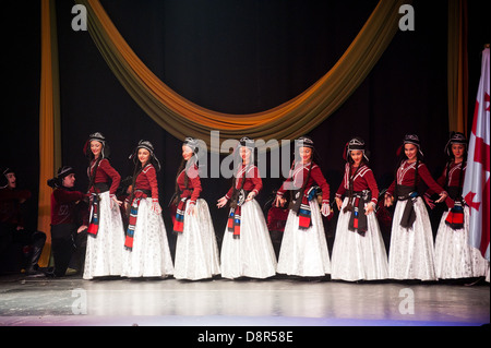 Georgian children dressed with traditional costumes dancing a folklore dance show on stage. Stock Photo