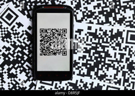 A mobile phone next to a QR code printed on paper Stock Photo