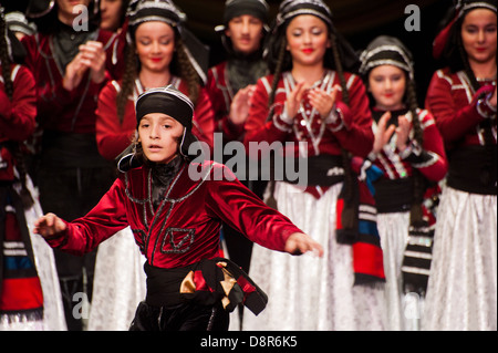 Georgian children dressed with traditional costumes dancing a folklore dance show on stage. Stock Photo