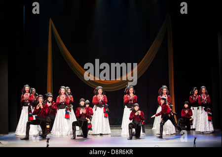 Georgian children dressed with traditional costumes dancing a folklore dance show on stage. Stock Photo