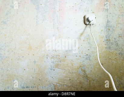 Electric socket and cable on grunge wall Stock Photo