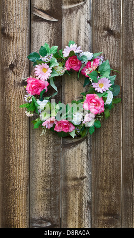 Floral wreath hanging on rustic wooden fence Stock Photo