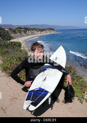 Surfer looks at waves from trail leading to Point Dume State Beach at Point Dume State Reserve Stock Photo