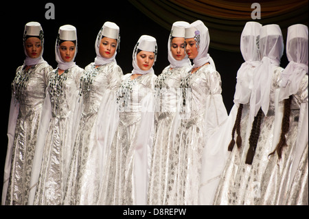 Georgian children dressed with traditional costumes dancing a folklore dance show on stage. Stock Photo