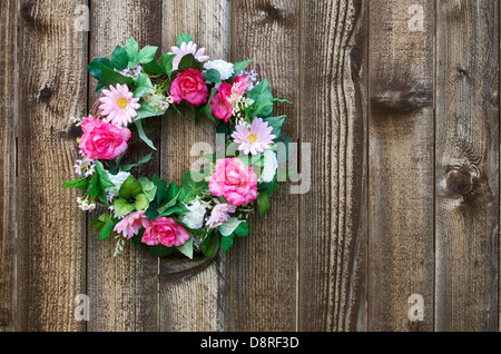 Flower wreath hanging on rustic wooden fence Stock Photo