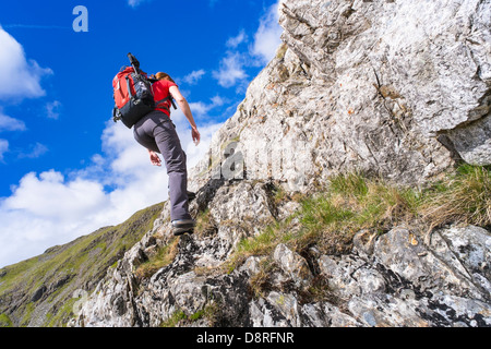 A hiker climbing Cam Crag Ridge in the Langstrath valley leading to the summit of Glaramara in the Lake District, Cumbria. Stock Photo