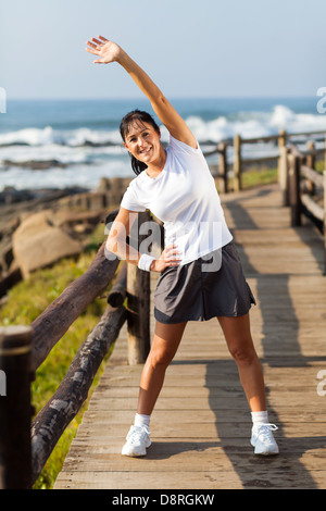 healthy mid age woman doing morning stretching at beach Stock Photo