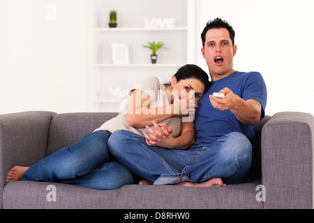 young couple watching scary horror movie at home Stock Photo