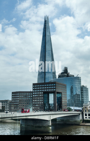 View of Red London bus going over London Bridge with the new Shard tall building and other modern buildings in the background Stock Photo
