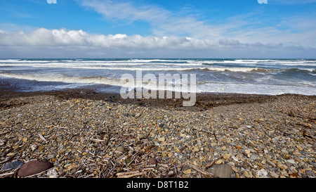 Taking in the sights of the Sea of Okhotsk from Abashiri with cloudy blue sky and gushing waves and pebbled beach Stock Photo