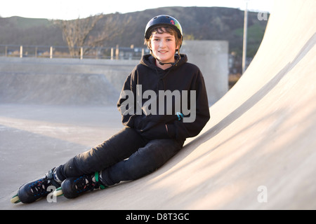 A Young Inline skater sitting down in a concrete skate park. Stock Photo